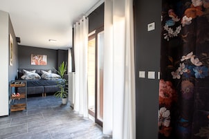 Een moderne woonkamer met een grijze bank, een potplant en een groot raam.