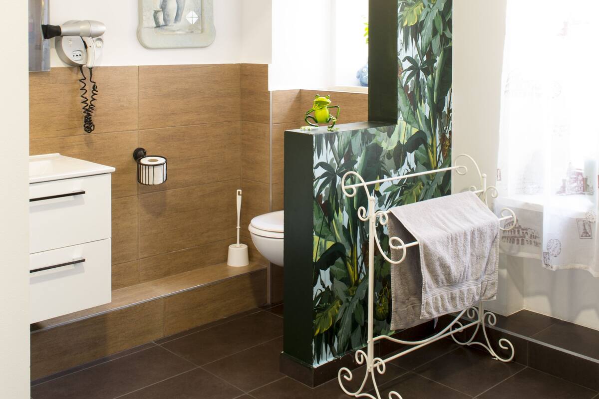 A bathroom with a large mirror, a toilet, a sink, and a shower area.