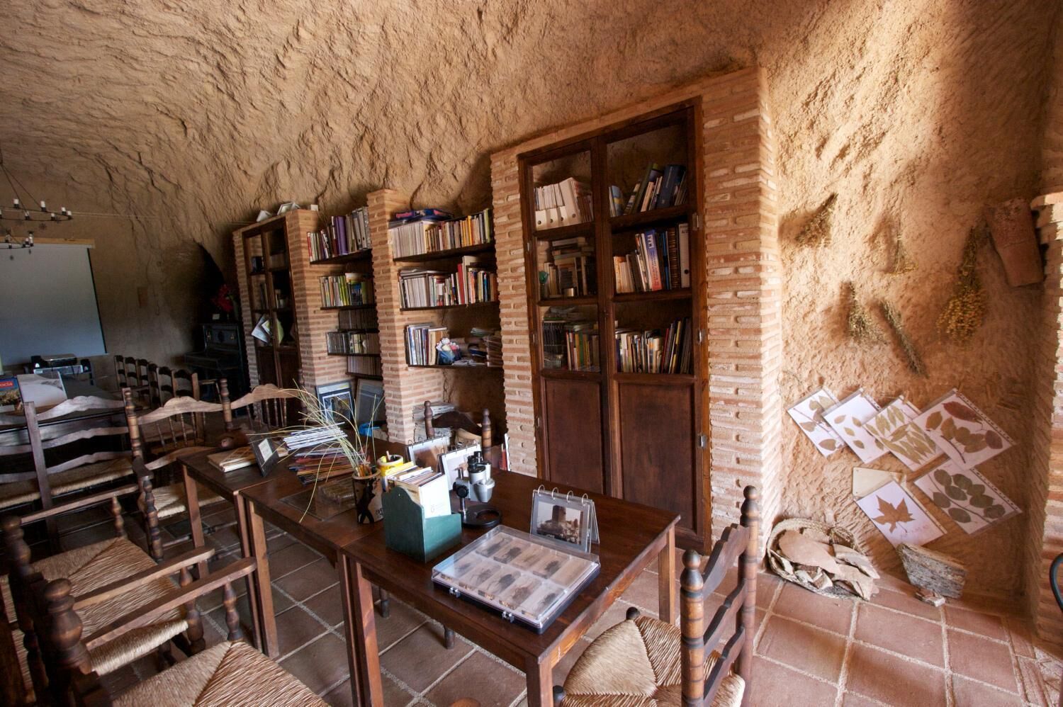 Una habitación rústica con pared de ladrillo, muebles de madera y estanterías llenas de libros.