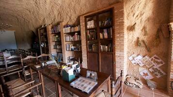 Una habitación rústica con pared de ladrillo, muebles de madera y estanterías llenas de libros.