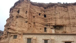 Un edificio con fachada de piedra y varias ventanas, algunas con contraventanas.