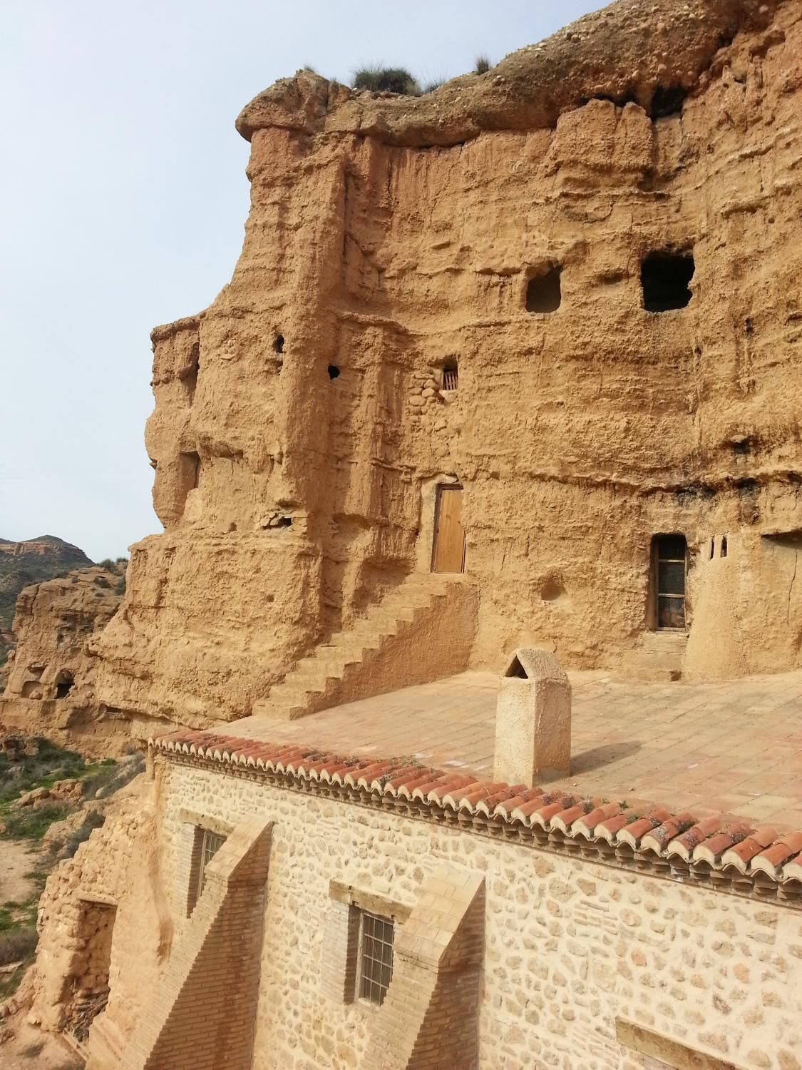 A traditional stone building with a flat roof and a staircase leading up to a terrace.