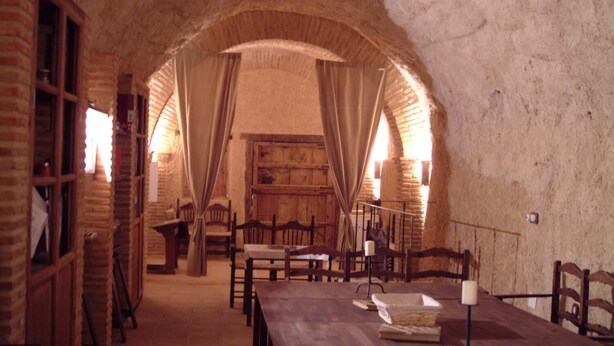 Una habitación rústica con paredes de ladrillo, muebles de madera y un amplio arco.