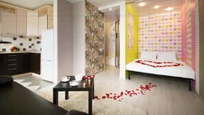 A modern kitchen with dark cabinets, a white refrigerator, and a dining area with a table set for two. - PaulMarie Apartments in Bobruisk (Bobruysk)