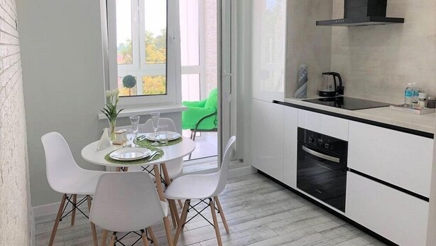 A modern kitchen with white cabinets, a black stove, and a window with a view of trees. - PaulMarie Apartments in Bobruisk (Bobruysk)