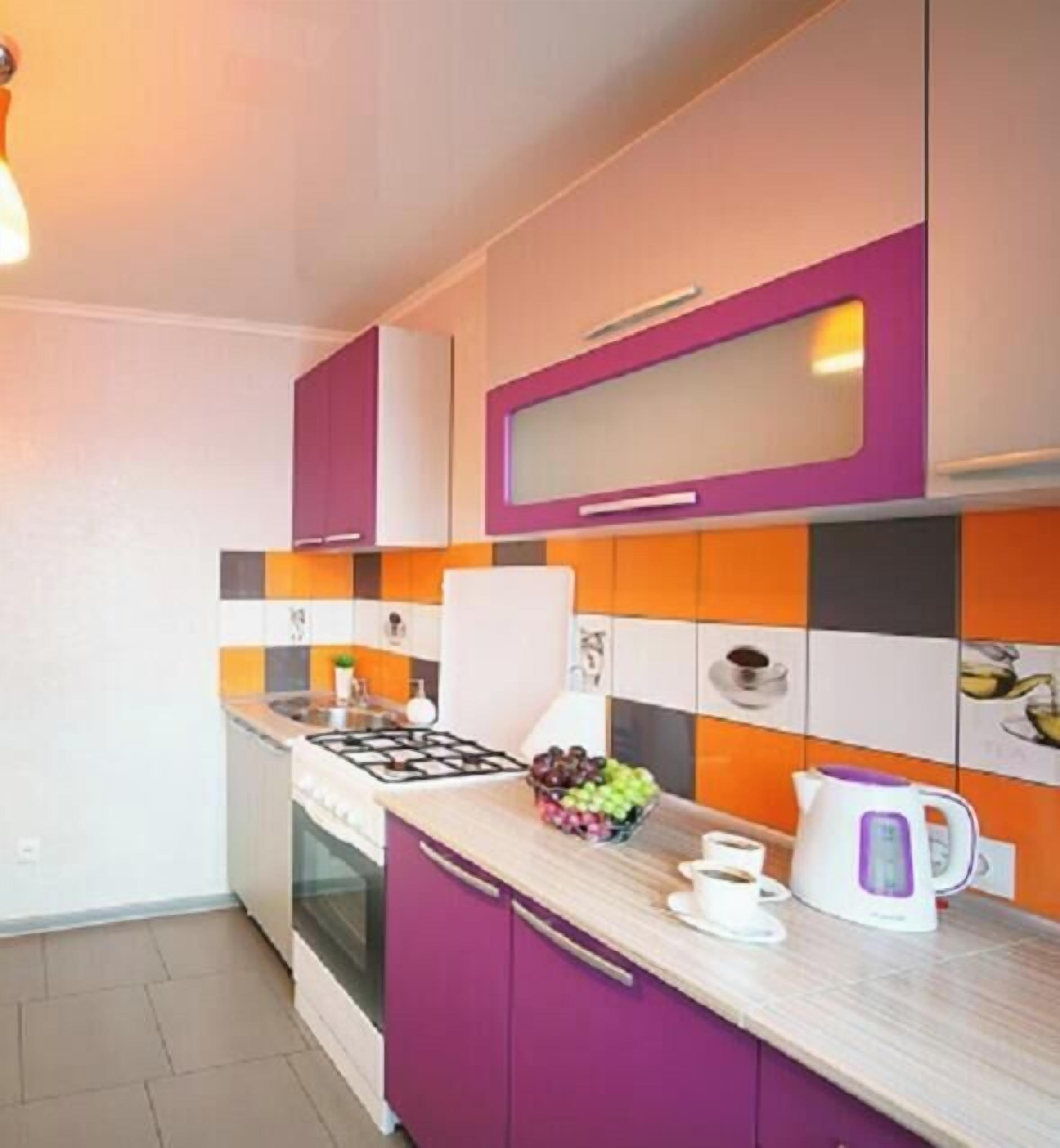 Una cocina moderna con gabinetes morados, una estufa a gas, una cafetera y un frutero.