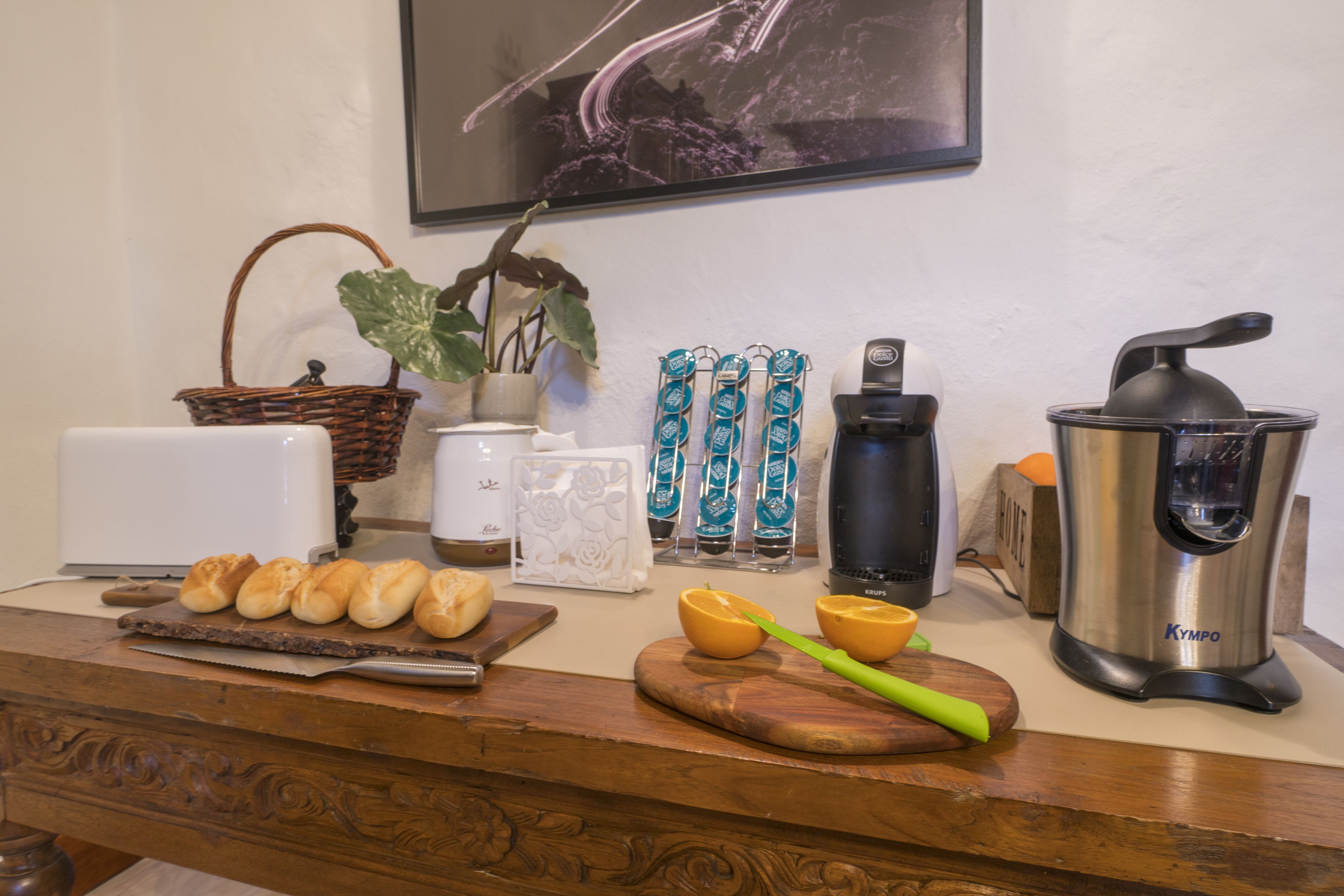 A kitchen counter with bread, a plant, a coffee maker, and a juicer.