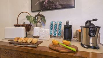 A kitchen counter with bread, a plant, a coffee maker, and a juicer.