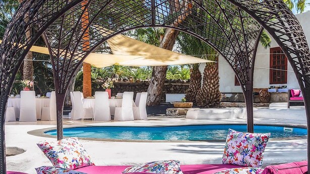 A poolside area with a covered seating area, a pool, and a view of the surrounding landscape. - Delmás Hotel Emblemático (Haria)