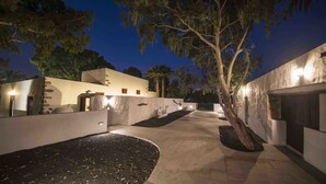 A well-lit outdoor pathway with a tree, stone walls, and a building with a flat roof. - Delmás Hotel Emblemático (Haria)