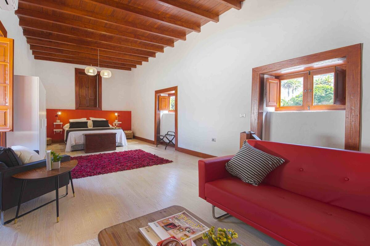 A modern living room with a red sofa, a wooden coffee table, and a red rug.