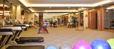 Un gimnasio con cintas de correr, pelotas de ejercicio y máquinas de pesas.