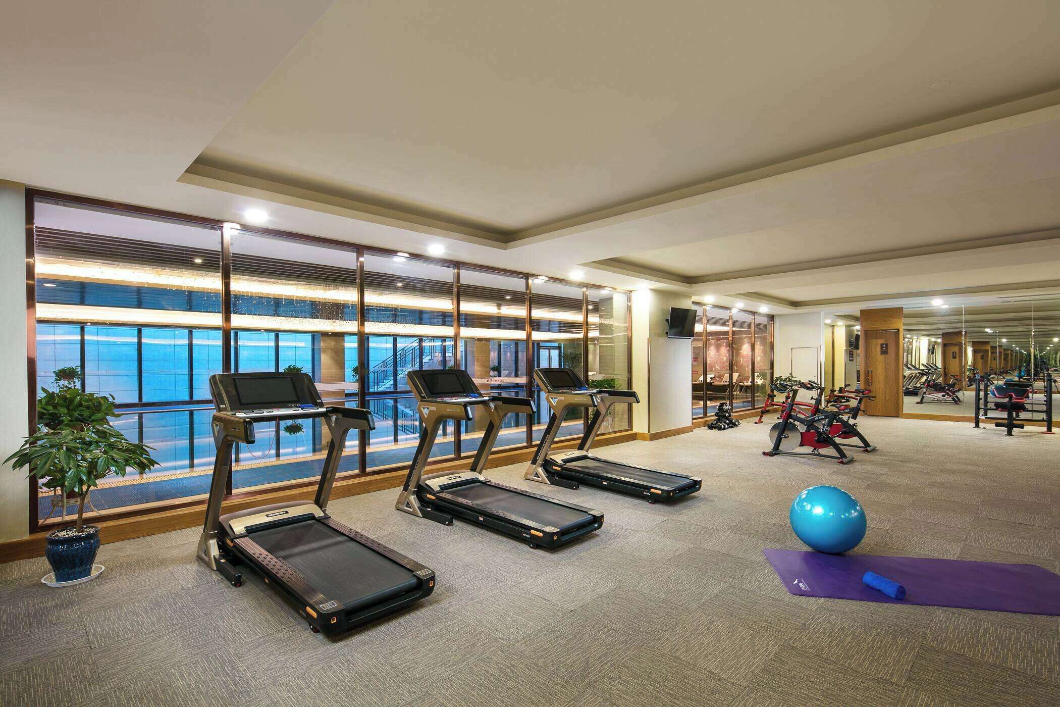 Ein Fitnessraum mit Laufbändern, Gymnastikbällen und einer Yogamatte.