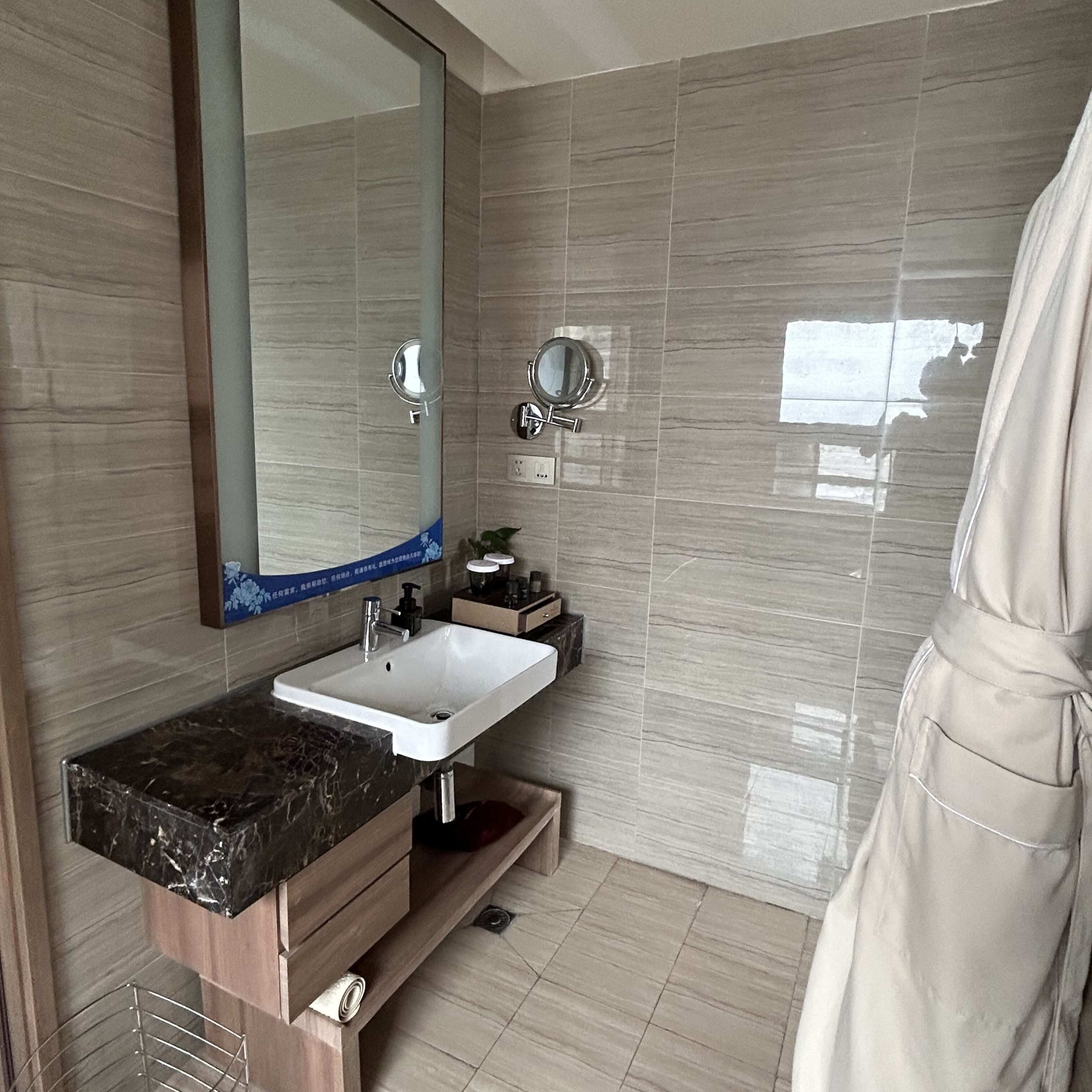 Un baño moderno con encimera de mármol, un espejo grande, un lavabo y una zona de ducha.