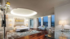 A spacious bedroom with a large bed, a glass dining table, and a city view.