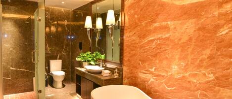 Un baño moderno con una bañera independiente, un box de ducha de vidrio, un revestimiento de mármol y un espejo grande.