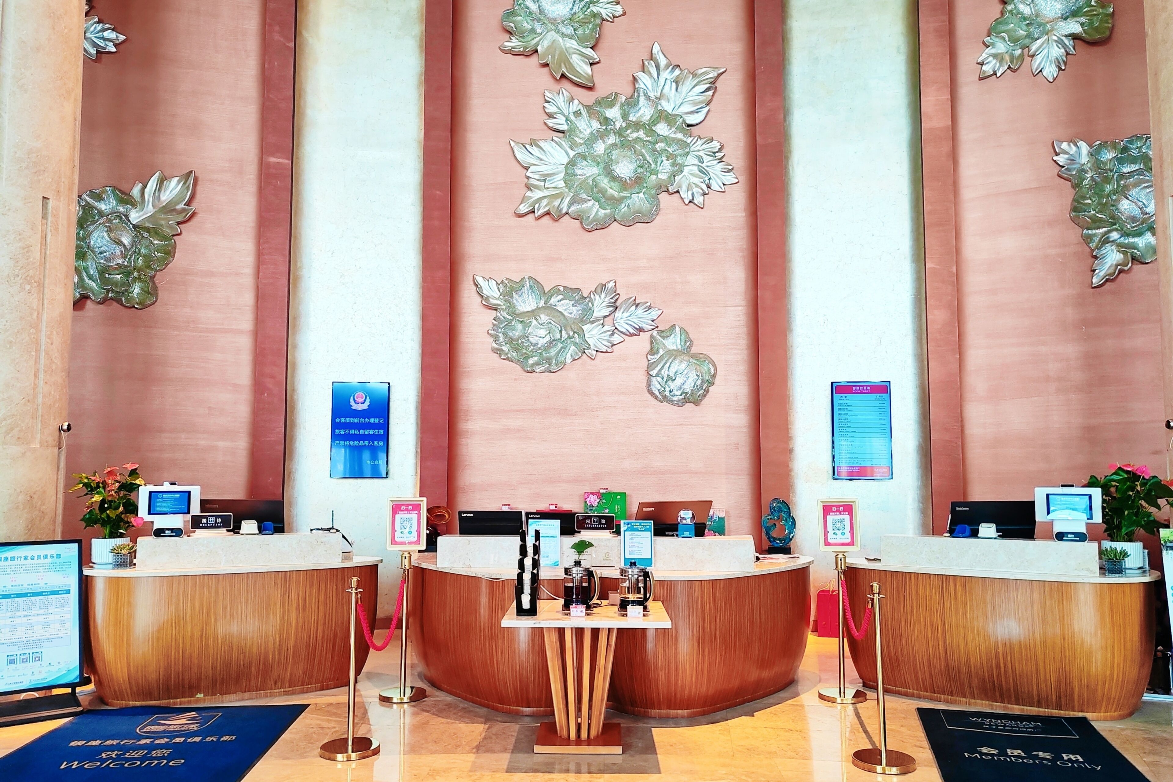 A reception area with a curved wooden reception desk, a digital screen, and a blue welcome mat.