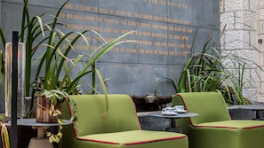 A seating area with green upholstered chairs and a small table with a teapot and cups. - Bat Sheva Jerusalem By Jacob (Jerusalem)
