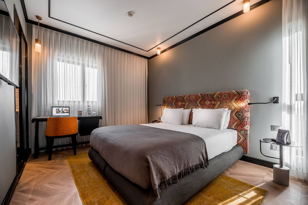 A modern hotel room with a large bed, a desk, and a chair.