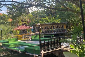 Un restaurant situé au bord de la rivière, doté d’une terrasse, d’un petit pavillon et d’une végétation luxuriante.