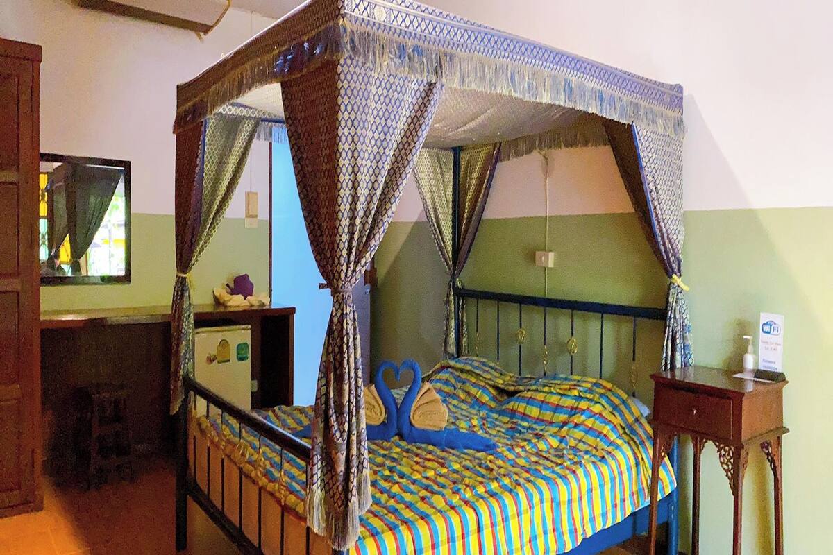 A four-poster bed with a canopy, a bedside table, and a mirror on the wall.