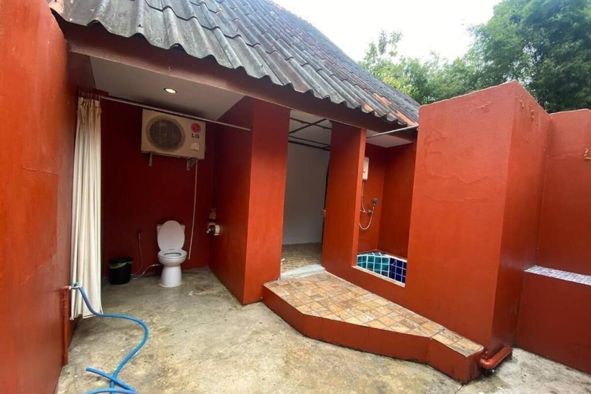 A small, enclosed bathroom with a toilet, a shower area, and a tiled floor.