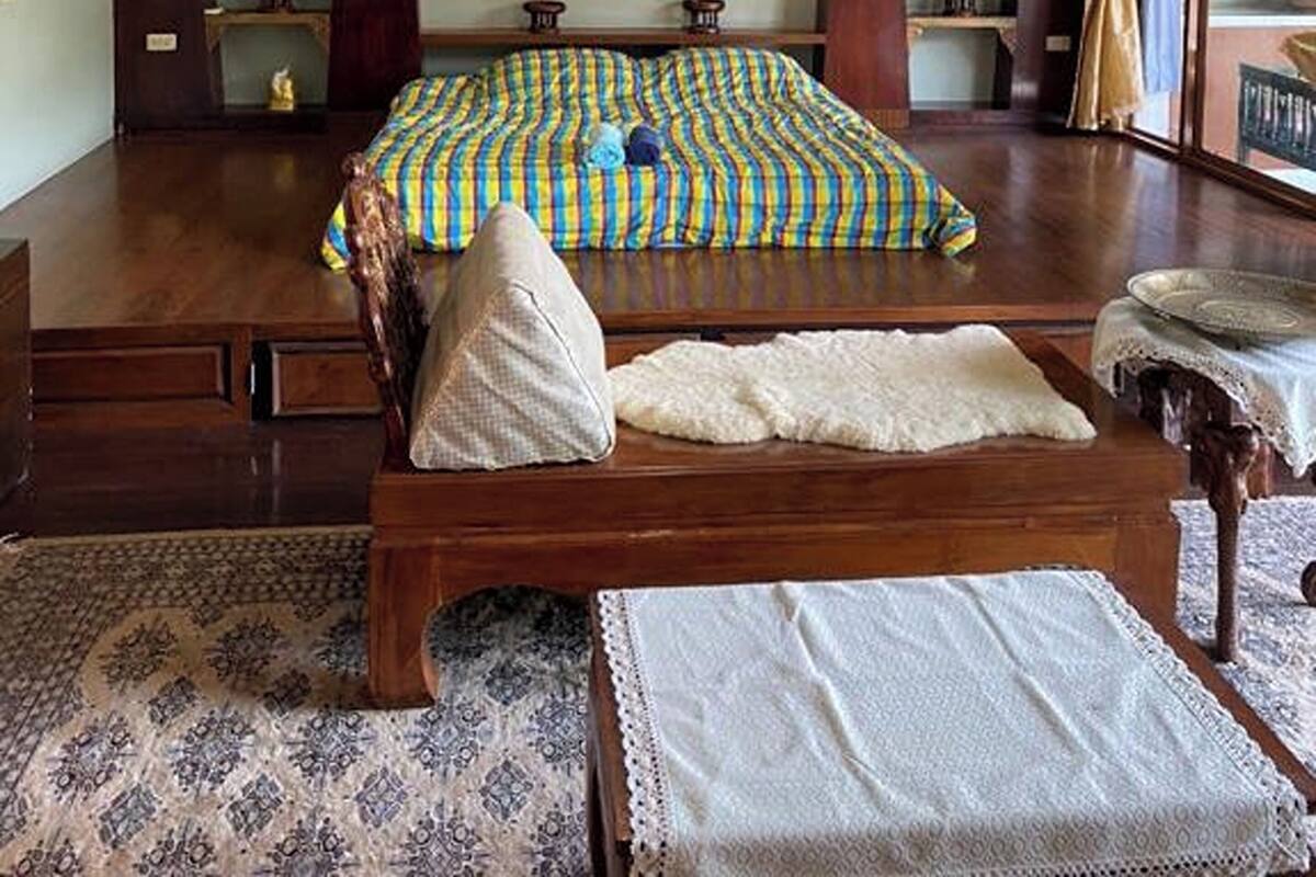 A bedroom with a bed, a large wall hanging, and a window with curtains.