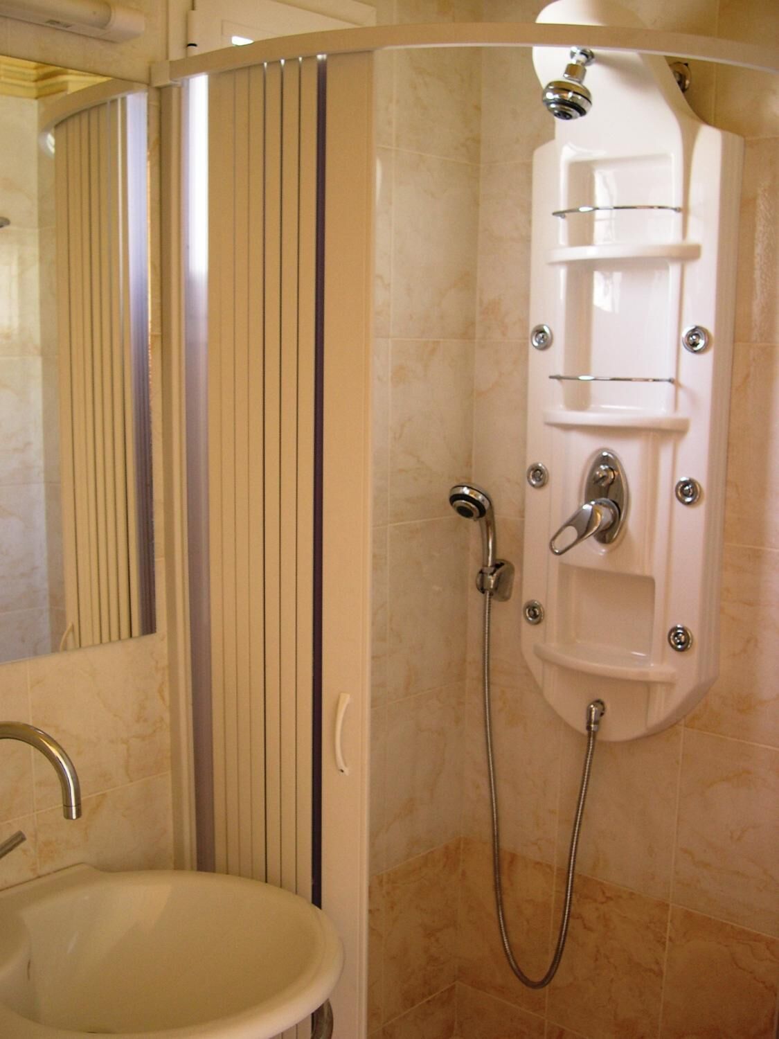 Un bagno con doccia, lavandino e specchio.