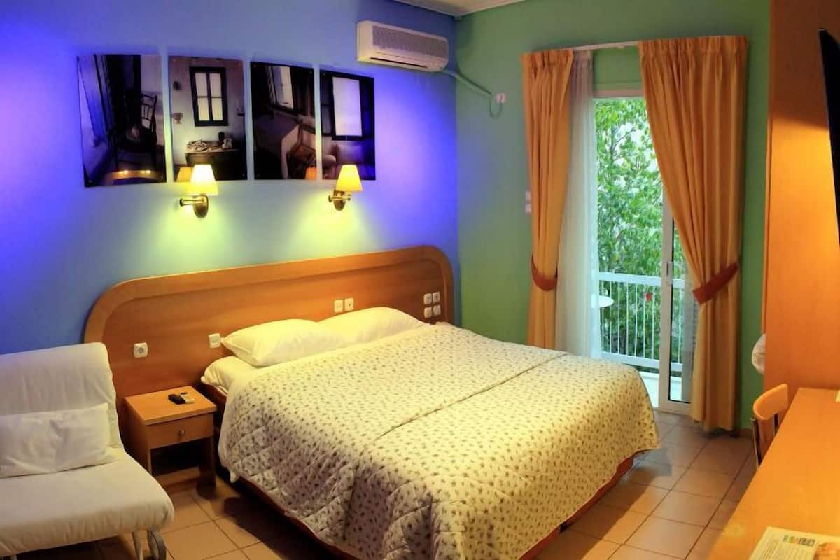 A bedroom with a bed, bedside table, chair, and a window with curtains.