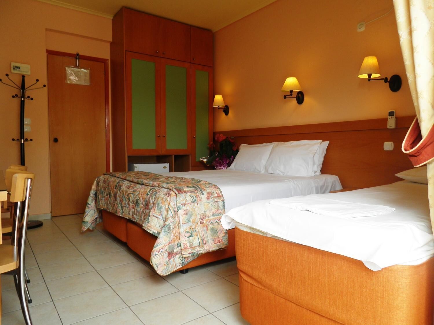 Una habitación de hotel con dos camas, un armario de madera, un escritorio y una silla.