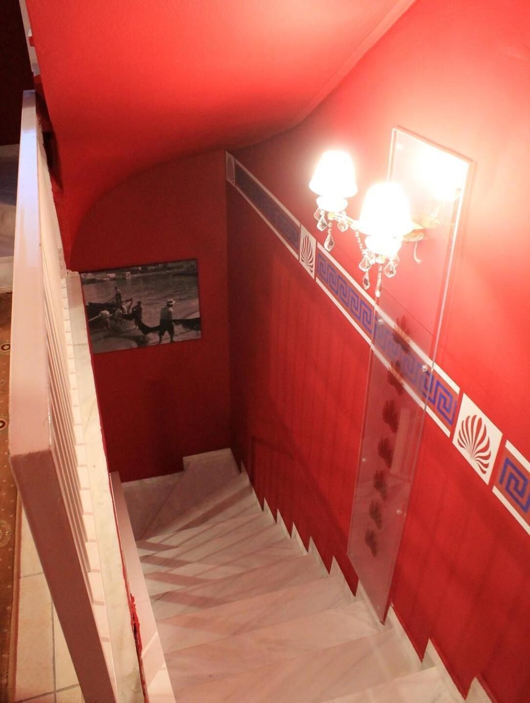 Un escalier aux murs rouges, orné d’une fresque et d’un éclairage décoratif mural.