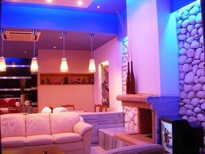 A modern interior with a sofa, a fireplace, and a stone wall. - Hotel Segas (Loutraki-Agioi Theodoroi)