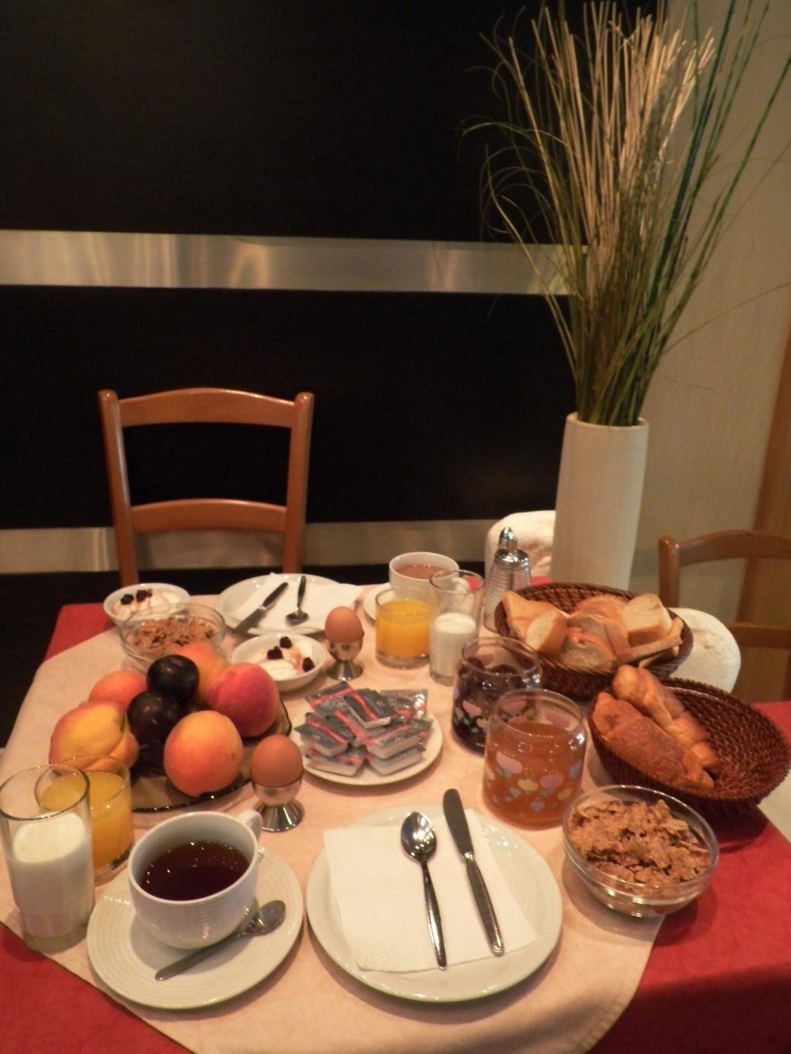 Una mesa de desayuno con frutas, pan, cereales y bebidas.
