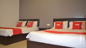 Two twin beds with red pillows and a white bedspread, a nightstand, and a wall-mounted air conditioning unit. - OYO 89715 CK Hotel 2 (Lumut)