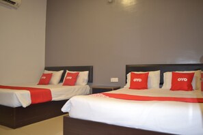Two twin beds with red and white bedding, a dark headboard, and a small bedside table. - OYO 89715 CK Hotel 2 (Lumut)