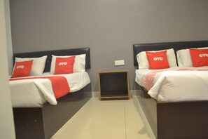 Two single beds with black headboards and red accents, a nightstand, and a neutral gray wall.