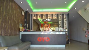 A hotel reception area with a modern design, featuring a reception desk with the hotel's name, a sofa, and a clock on the wall. - OYO 89715 CK Hotel 2 (Lumut)