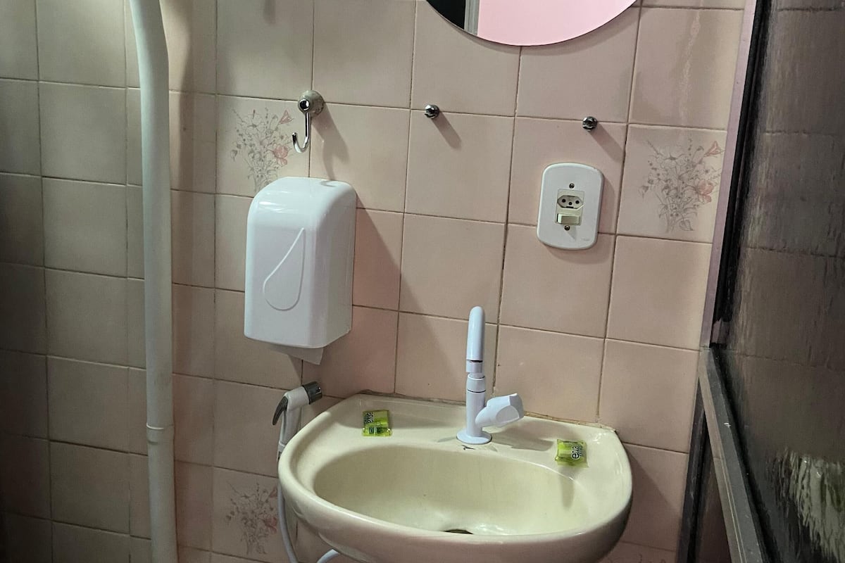 A bathroom with a toilet, sink, and a mirror.