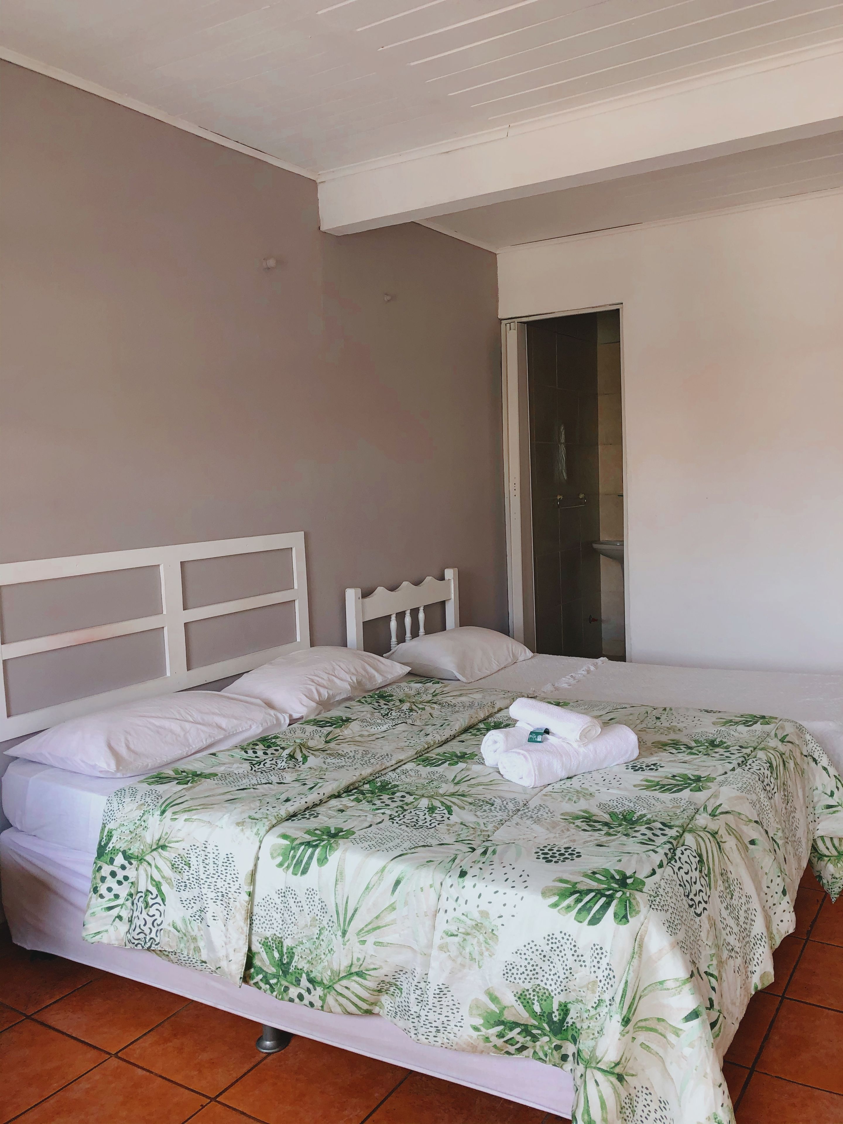 Un lit simple avec une couvre-lit à motifs floraux, une tête de lit blanche et des oreillers.
