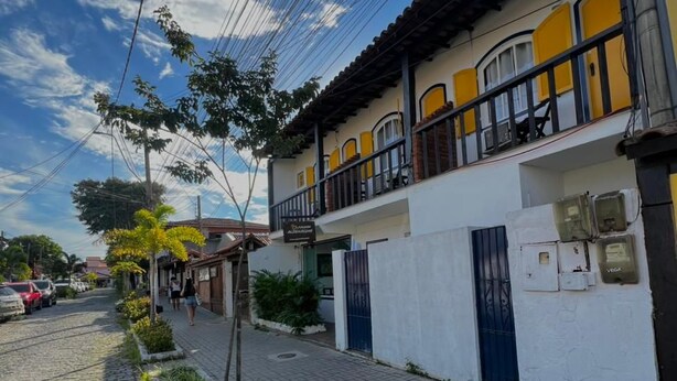 A residential building with a balcony, a paved street, and a cobblestone path.