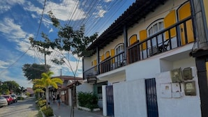 A residential building with a balcony, a paved street, and a cobblestone path. - Pousada Aldeia Buzios (Búzios)
