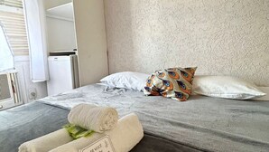 A hotel room with a bed, pillows, a towel, and a sign.