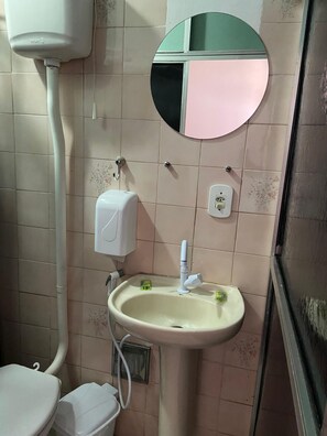 A bathroom with a toilet, sink, and a mirror. - Pousada Aldeia Buzios (Búzios)