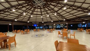 Un comedor amplio e interior con techos altos y un diseño geométrico. Las mesas y las sillas están dispuestas en una distribución simétrica.