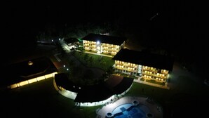 Un gran complejo hotelero, bien iluminado, de noche, con varias construcciones, una piscina y un área ajardinada.