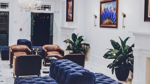 Um hall amplo com um grande sofá azul, um lustre e uma lareira.