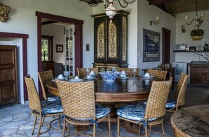 A dining area with a round wooden table surrounded by wicker chairs with blue cushions.