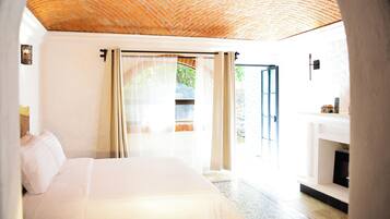 Un dormitorio con cama, chimenea y vistas al exterior.