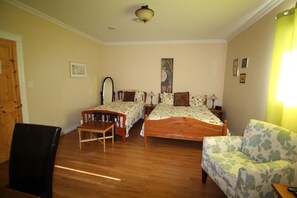 A bedroom with two single beds, a wooden chair, a sofa, and a wooden desk. - The Fiddle and The Sea B&B (Port Hood)