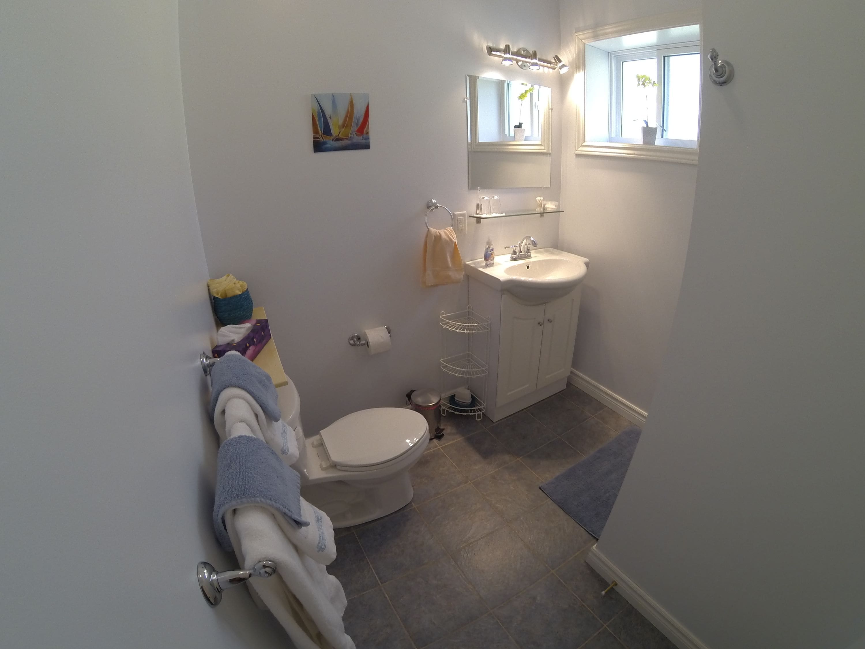 A compact bathroom with a toilet, sink, and a small shelf.
